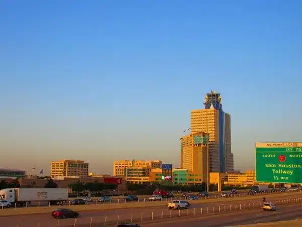 A busy highway with cars in motion, featuring a tall building rising in the background against a clear sky.